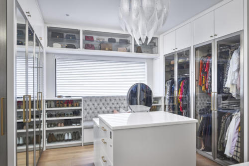 Walk in closet with custom cabinetry and glass display cabinets.